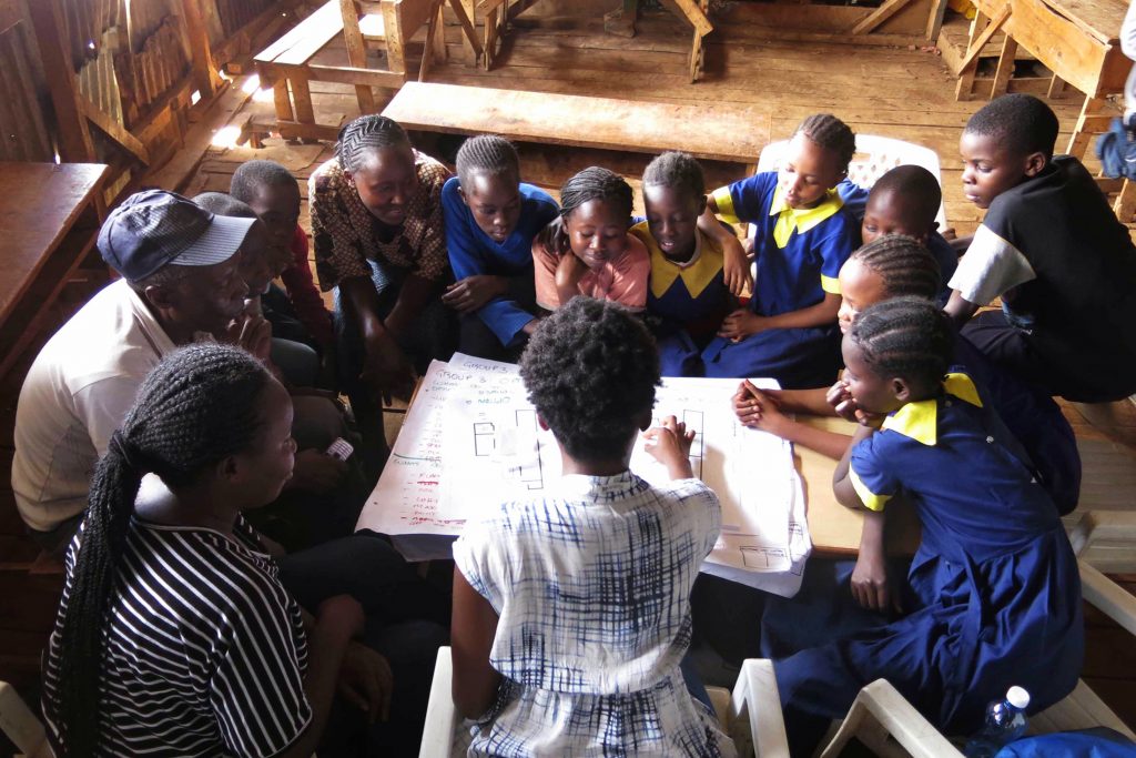 Children gathered around a table viewing a diagram