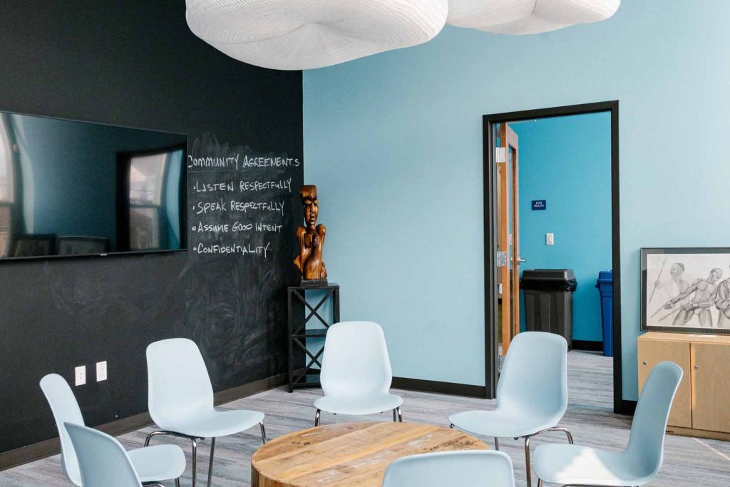 Black and blue room with a table, chairs, and television at Restore Oakland