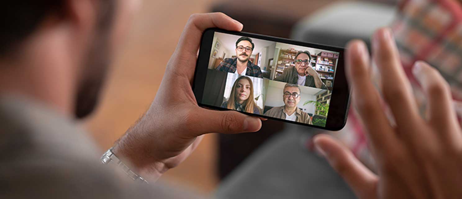 Man holding phone while on a video call with four others